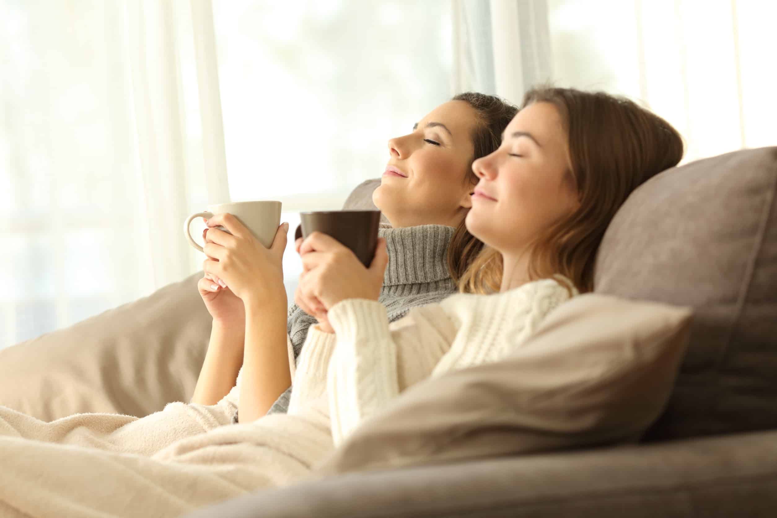 two women on a couch with eyes closed, breathing in the fresh air