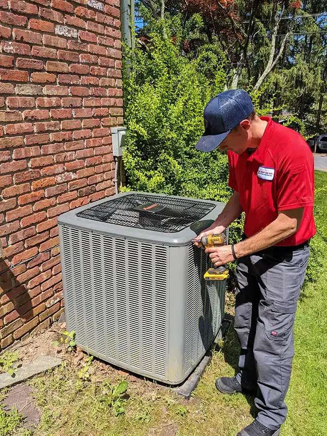 Mark Lindsay technician using drill on ac outside of a residential home.