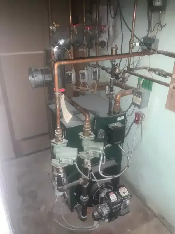Boiler system with copper piping, circulation pumps, and heating controls installed in a residential basement in West Milford