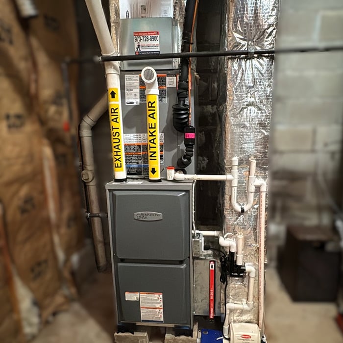 Armstrong Air high-efficiency gas furnace with labeled exhaust and intake pipes installed in NJ