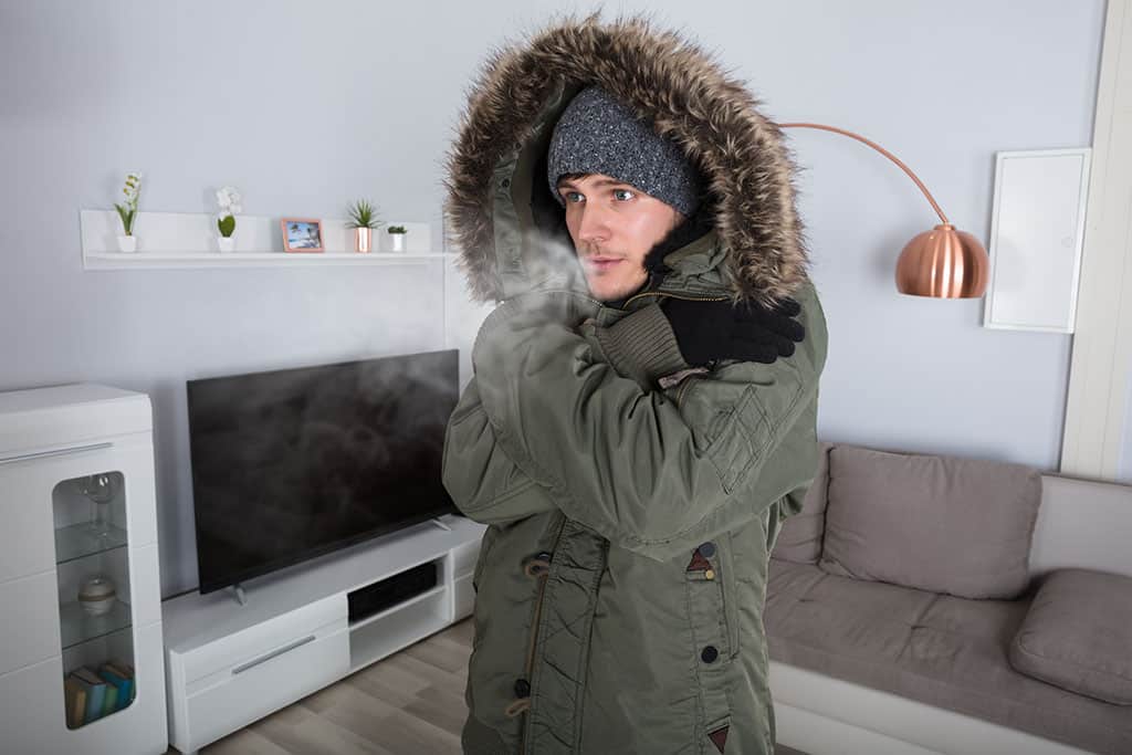 man wearing jacket inside because there's no heat at home