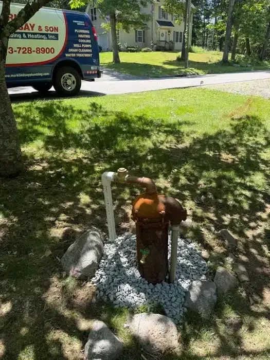 Corroded residential well casing ready for replacement with Mark Lindsay & Son Plumbing service van in the background