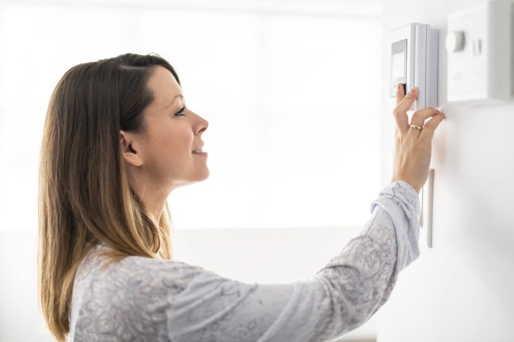 woman adjusting thermostat