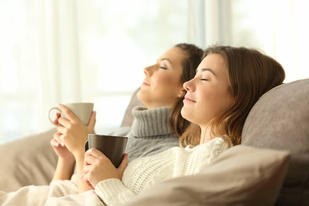 Two roommates relaxing on a sofa in the living room