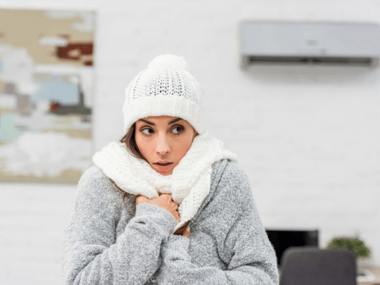 woman wearing winter jacket, hat and scarf inside because heater is broken