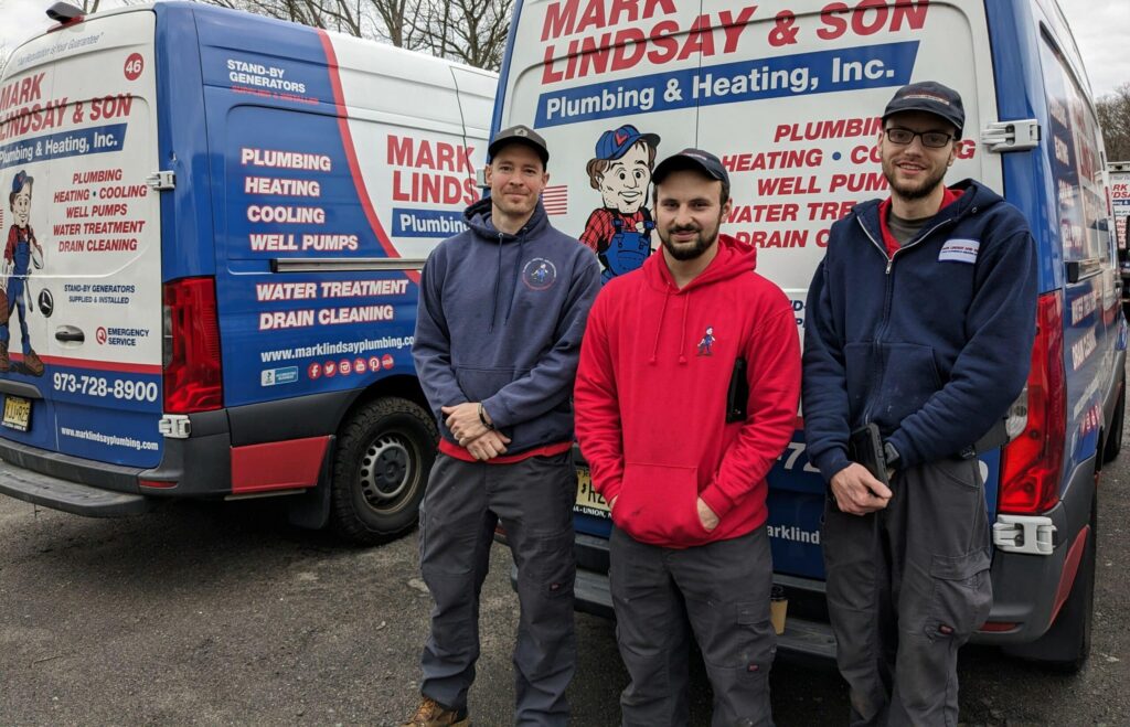 nj hvac and plumbing techs standing in front of service vans