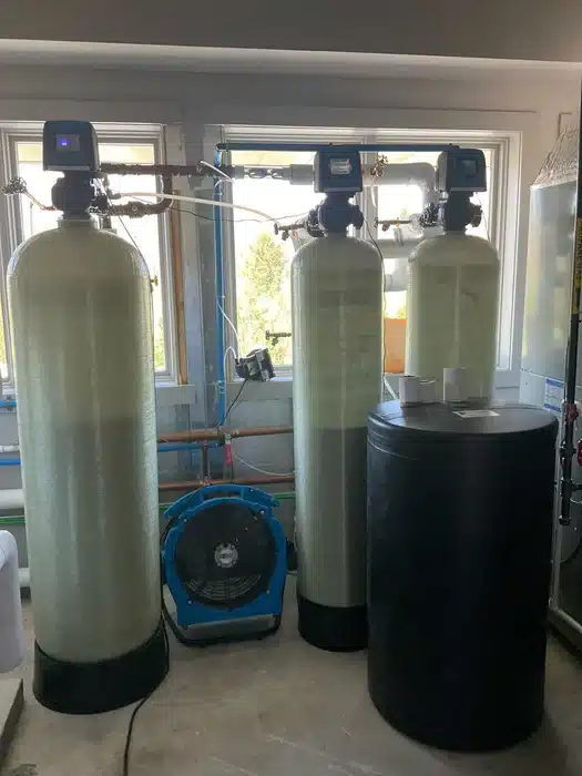 Three fiberglass filtration tanks and a brine tank treating whole-house water for a West Milford, NJ family